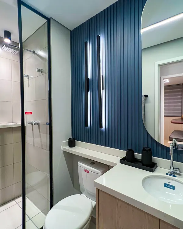 Banheiro do decorado com painel azul, espelho oval e box de vidro