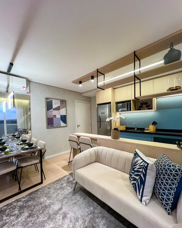 Sala de estar do decorado com sofá claro, mesa de jantar e cozinha integrada ao fundo